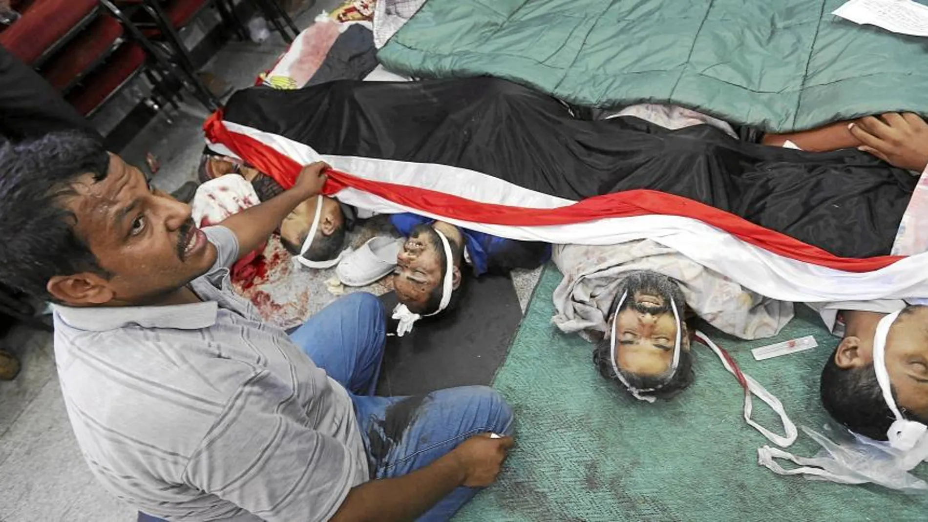 Un miembro de los Hermanos Musulmanes posa junto a varios de los seguidores de Mursi que fallecieron la madrugada de ayer, en El Cairo