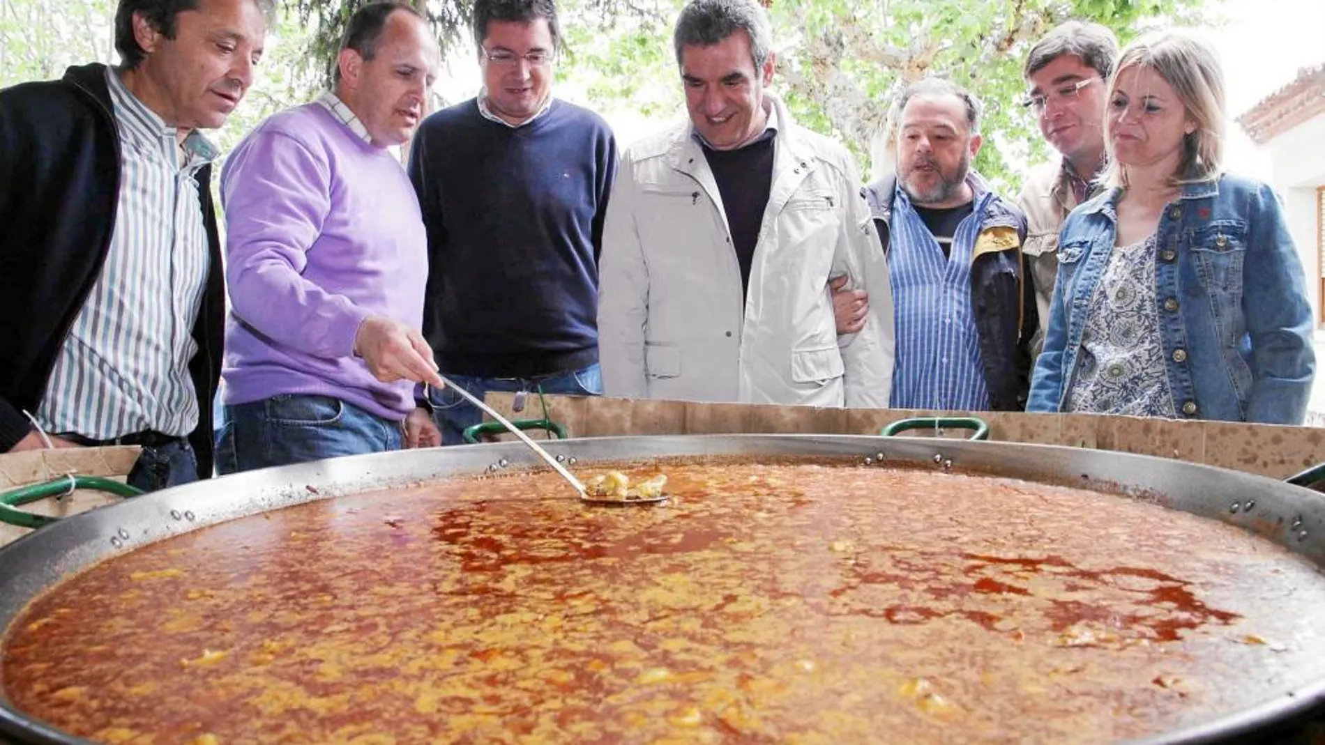 Los dirigentes del PSOE observan la paellera en la que se cocinó la comida que degustaron durante la Fiesta de la Rosa en Coca