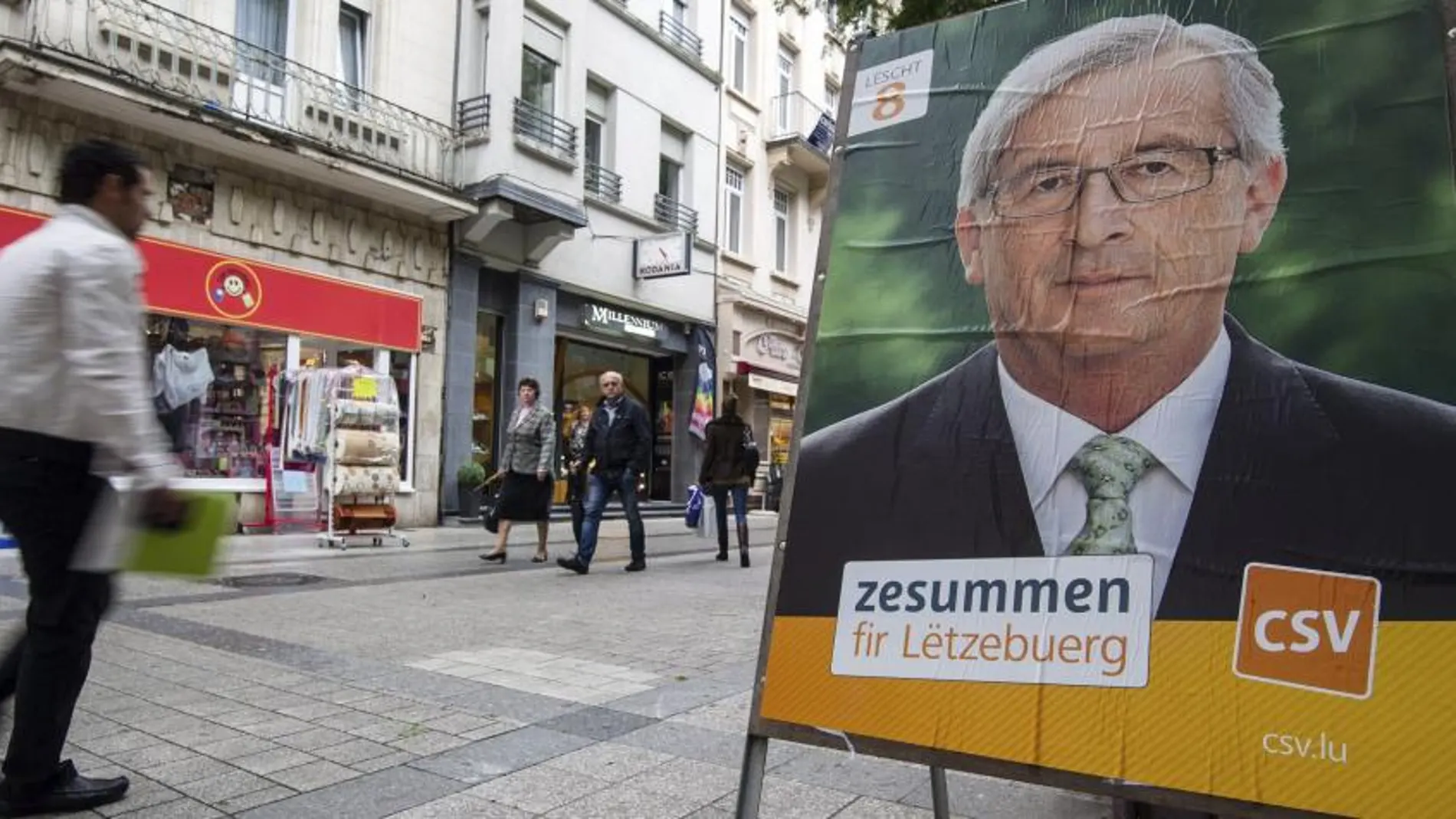 Un hombre pasa junto a un cartel electoral del actual primer ministro de Luxemburgo y candidato del CSV, Jean-Claude Juncker