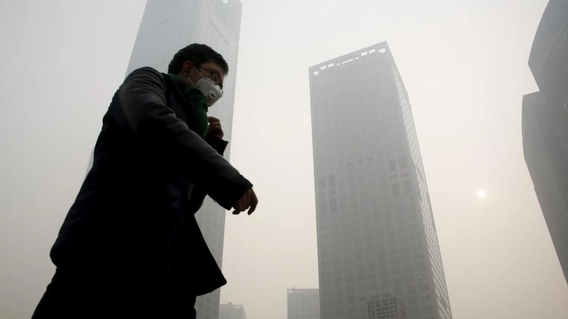 China es el mayor emisor de dióxido de carbono. En la imagen, un hombre con una máscara camina por el distrito financiero de Beijing / Foto: Reuters