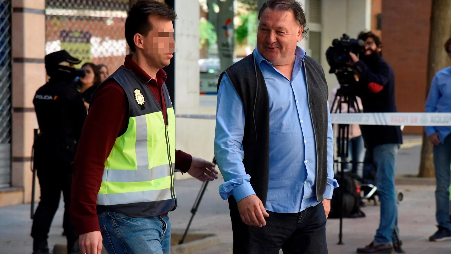 El presidente del Huesca, Agustín Lasaosa (d), junto a un policía a su salida de las oficinas del club tras ser detenido durante la "Operación Oikos"