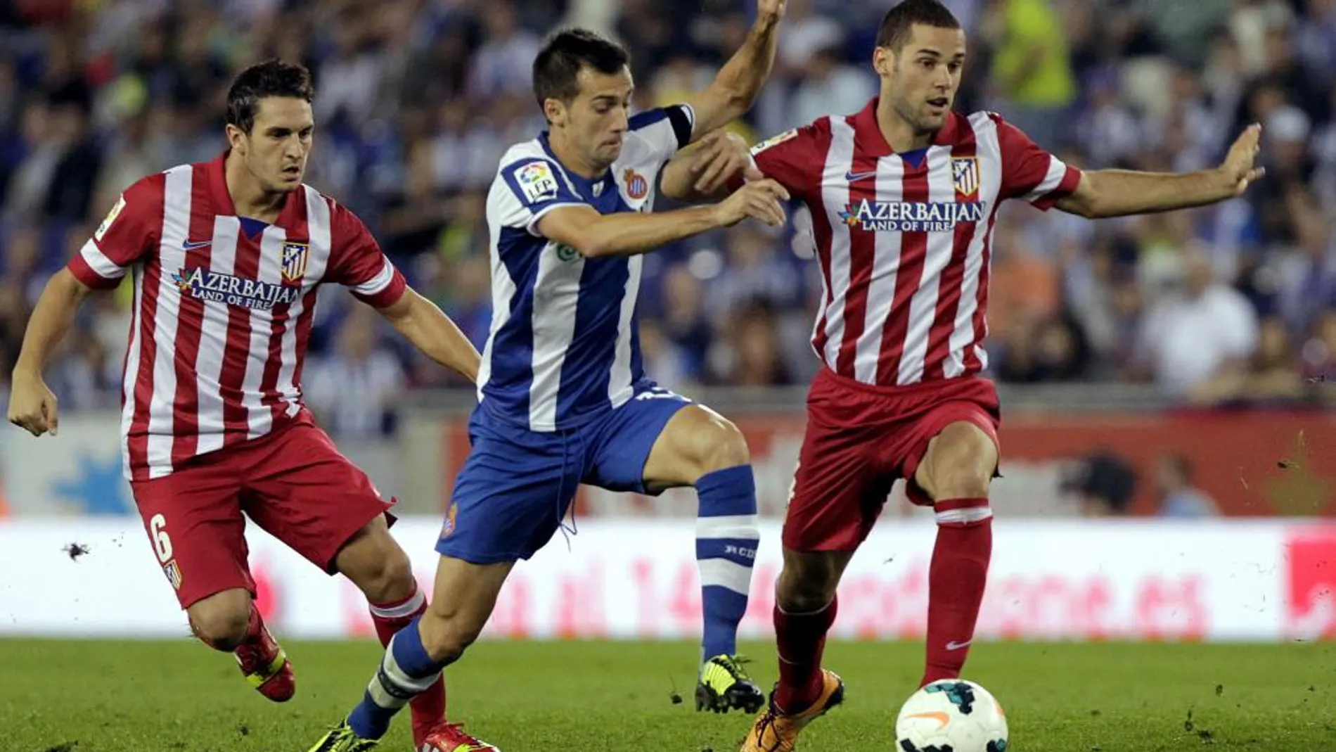 El centrocampista del Espanyol Manuel Lanzarote (c) y los jugadores del Atlético de Madrid "Koke"y Tobias Albertine luchan por el balón