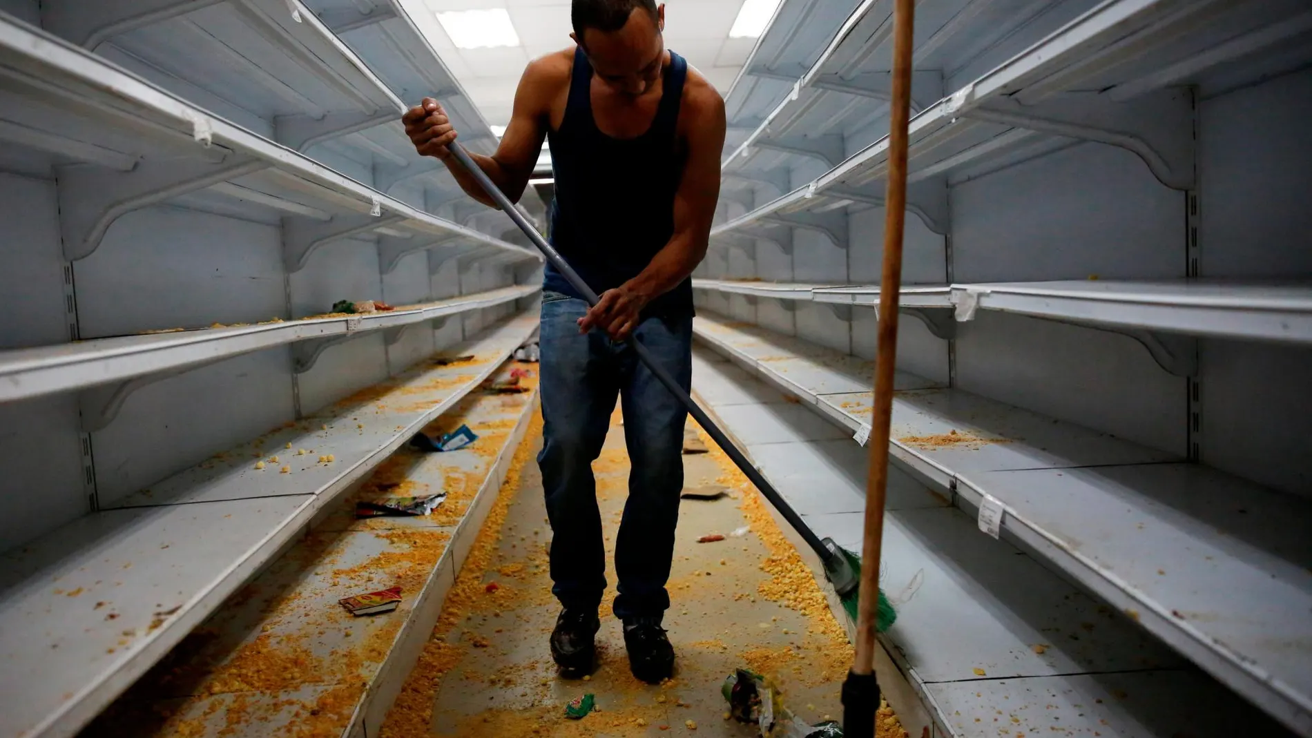 Un trabajador limpia un comercio saqueado en disturbios/Reuters