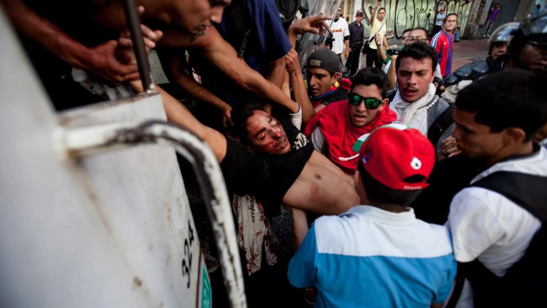 Un estudiante opositor muerto con un disparo en la cabeza es trasladado a un vehículo policial por otros estudiantes en la manifestación antigubernamental de Caracas