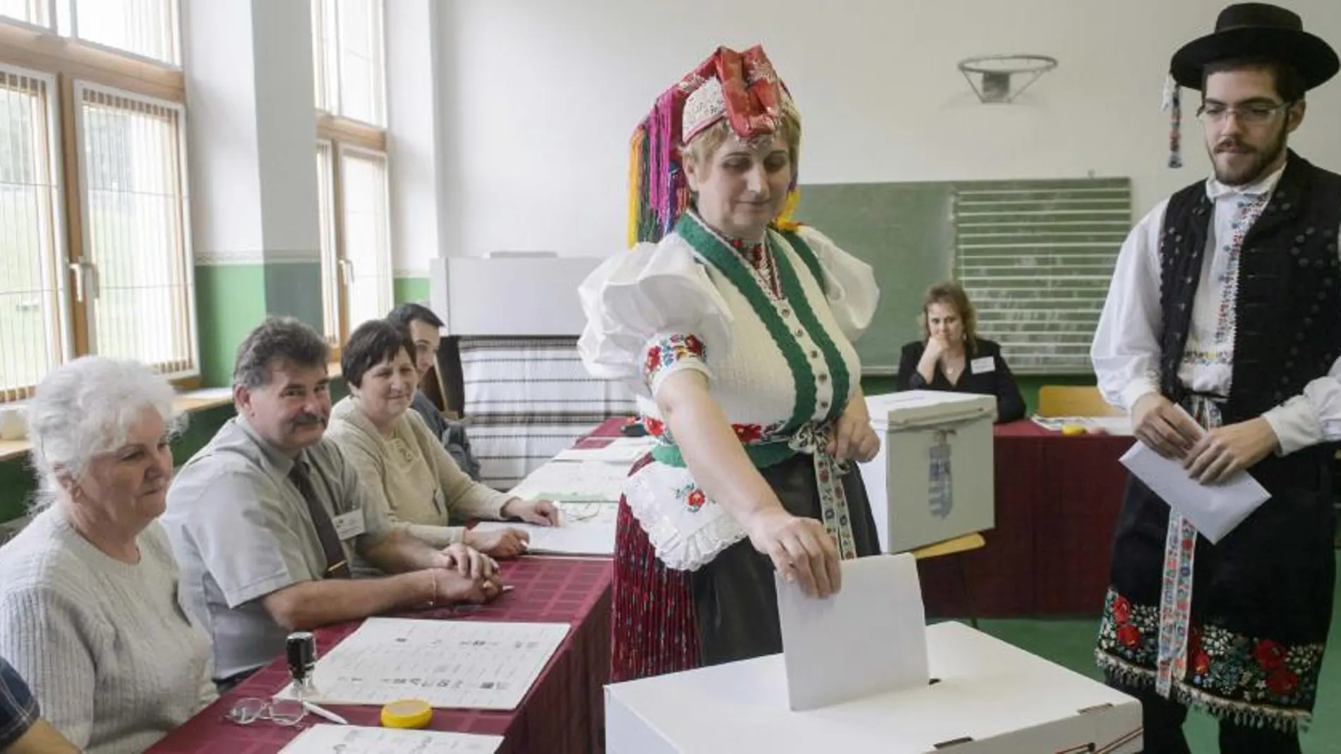 Una pareja de Holloko (Hungría), ataviados con trajes regionales, votan en un colegio electoral.