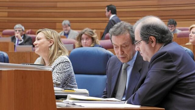 Juan Vicente Herrera y José Antonio de Santiago-Juárez dialogan en un Pleno de las Cortes. Al fondo la consejera de Hacienda, Pilar del Olmo