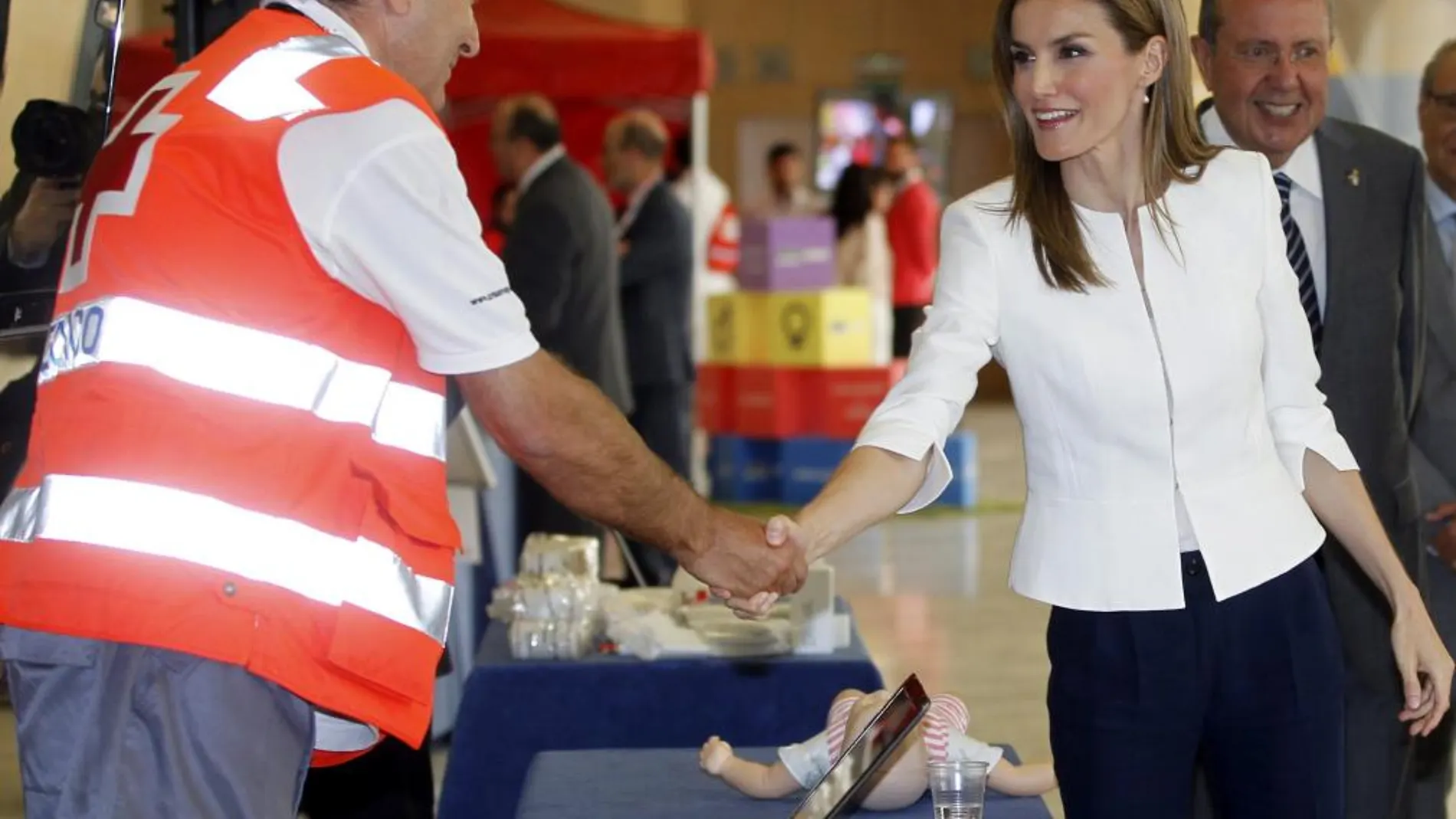 La Reina Letizia saluda a uno de los voluntarios durante el acto conmemorativo del 150 aniversario de la fundación de Cruz Roja.