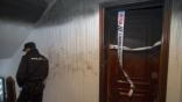 Un policía custodia la puerta del piso en el han fallecido una mujer y su nieta