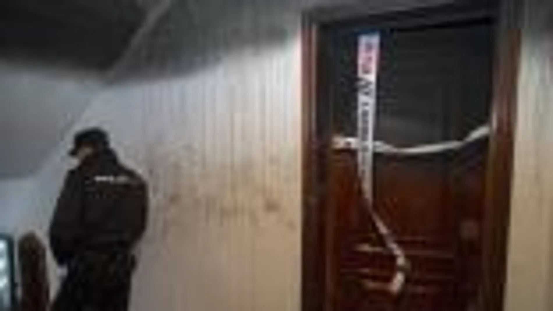 Un policía custodia la puerta del piso en el han fallecido una mujer y su nieta