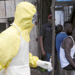 Varios jóvenes de Sierra Leona observan a un sanitario equipado con el mono que marca el protocolo para atender a enfermos de ébola