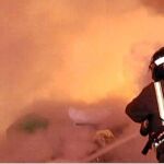 Un bombero de Alcorcón trata de sofocar las llamas de una hoguera en una de las montañas de basura