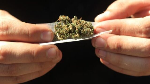 Una joven prepara un cigarrillo de marihuana