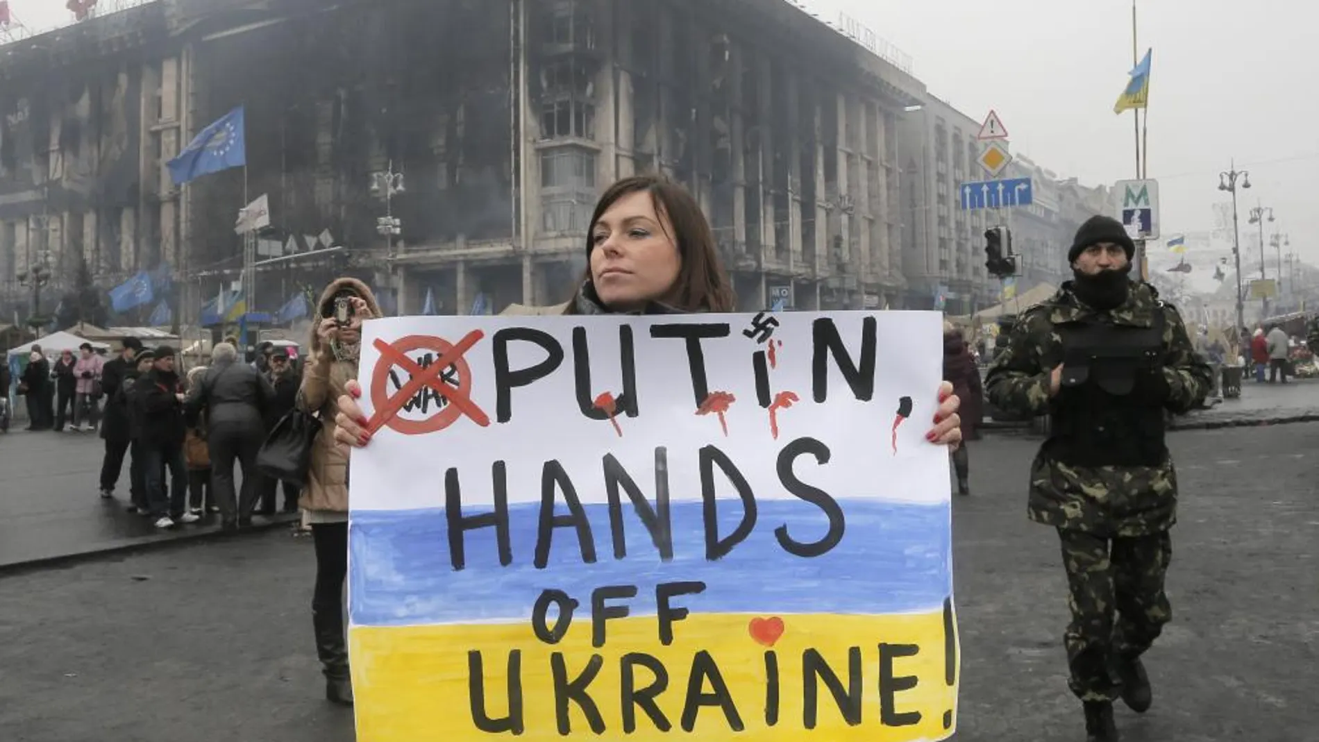 Una mujer muestra un cartel en Kiev en el que se puede leer: «Putin, las manos fuera de Ucrania».