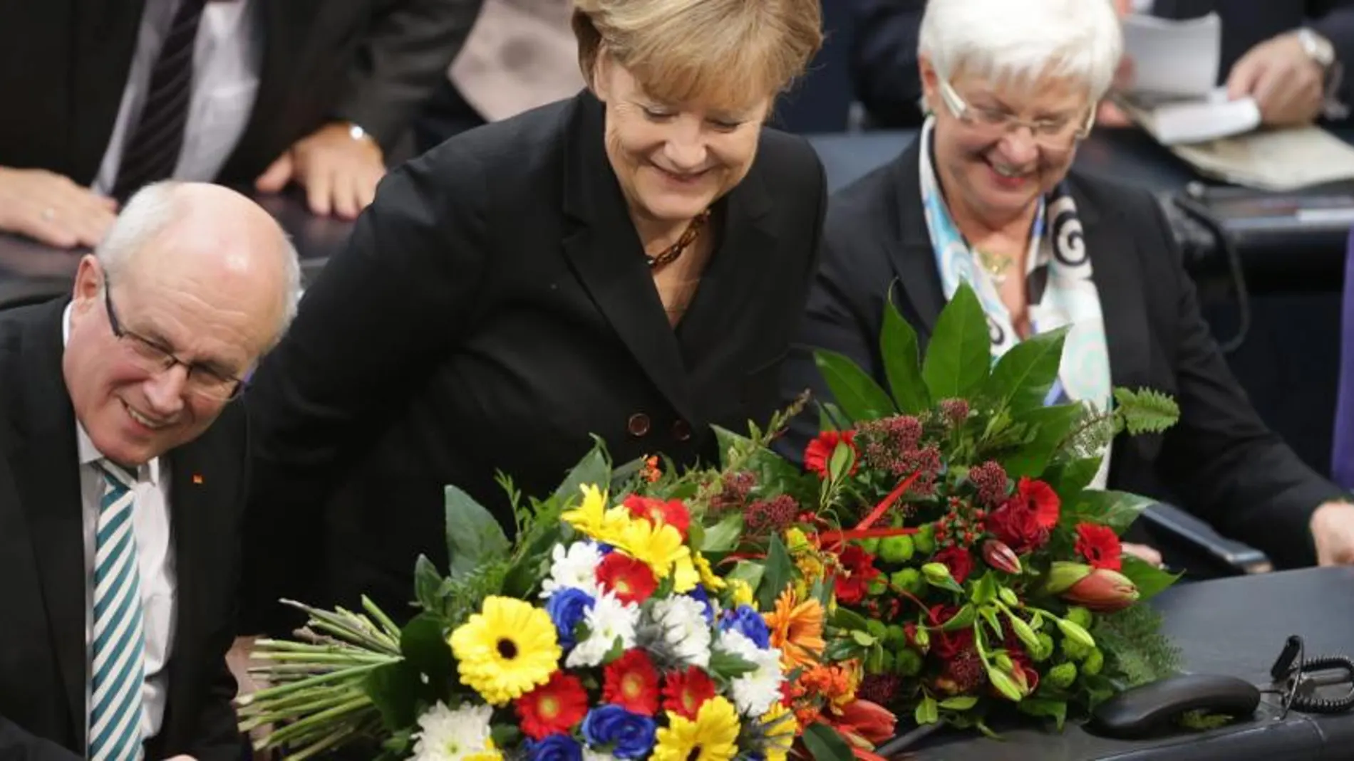 La canciller alemana, Angela Merkel (centro), recibe un ramo de flores en la Cámara Baja tras ganar los votos para su investidura en el Parlamento en Berlín (Alemania)