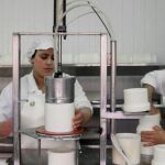 Dos empleados de la quesería artesanal en el proceso de maduración de los quesos curados que comercializa esta empresa familiar.
