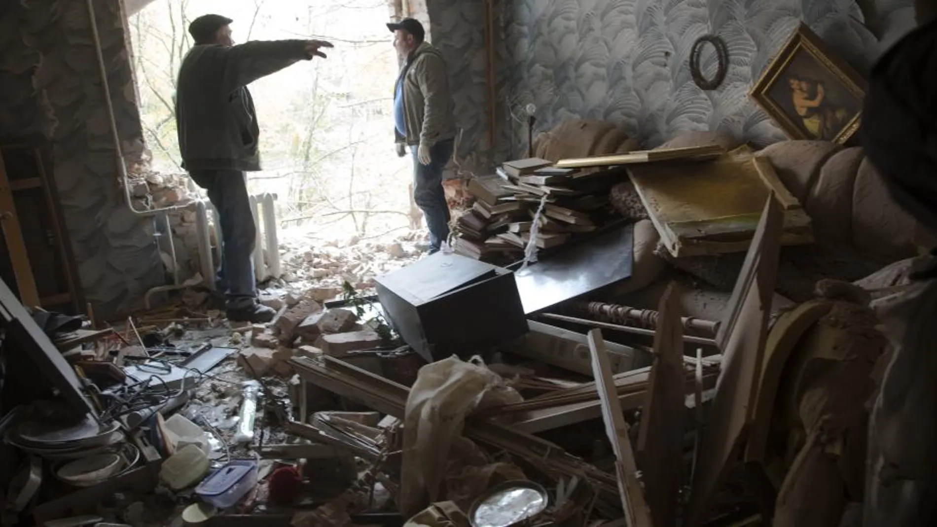 Dos personas charlan en una de las casas destruidas por un bombardeo en Donetsk.