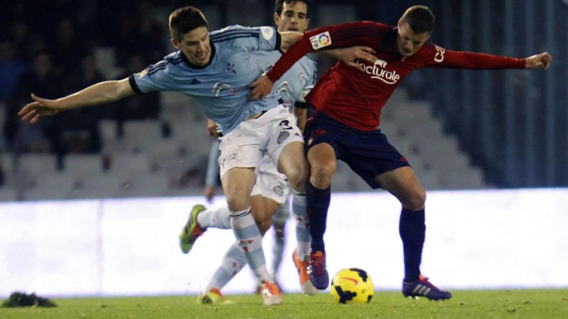 El defensa del Celta Andreu Fontàs (i) pugna por un balón con el delantero del Osasuna Oriol Riera (d).