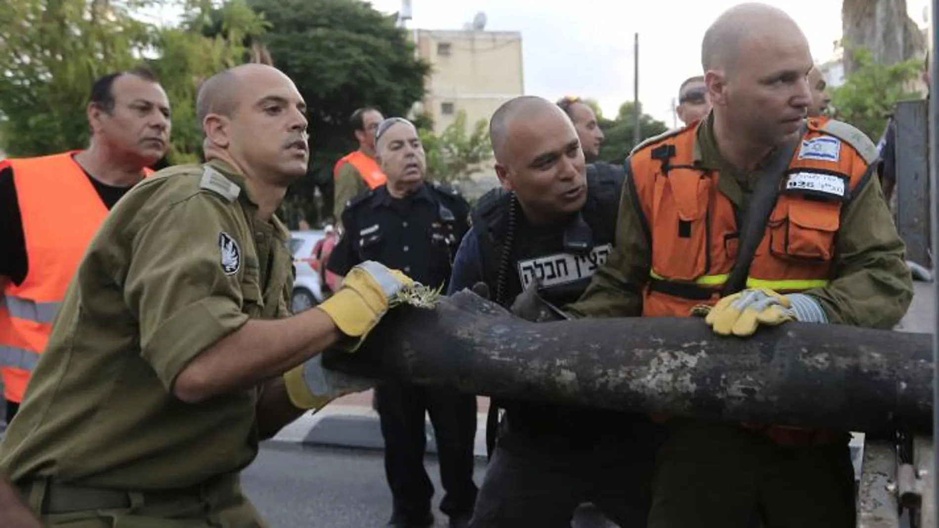 Policías y soldados israelíes retiran los restos de un cohete lanzado desde Gaza.