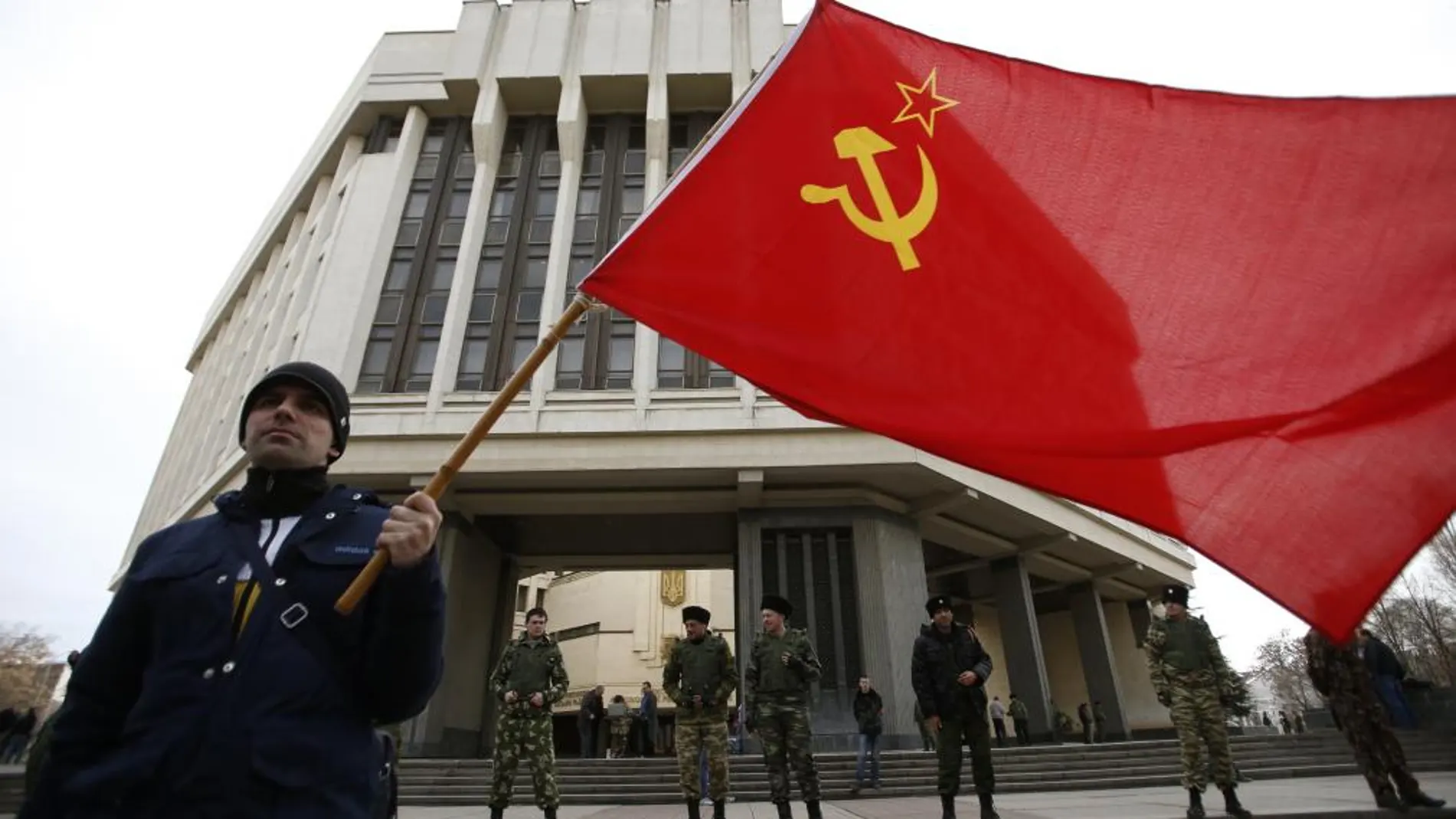 Ciudadanos crimeos posan con la antigua bandera soviética frente al parlamento
