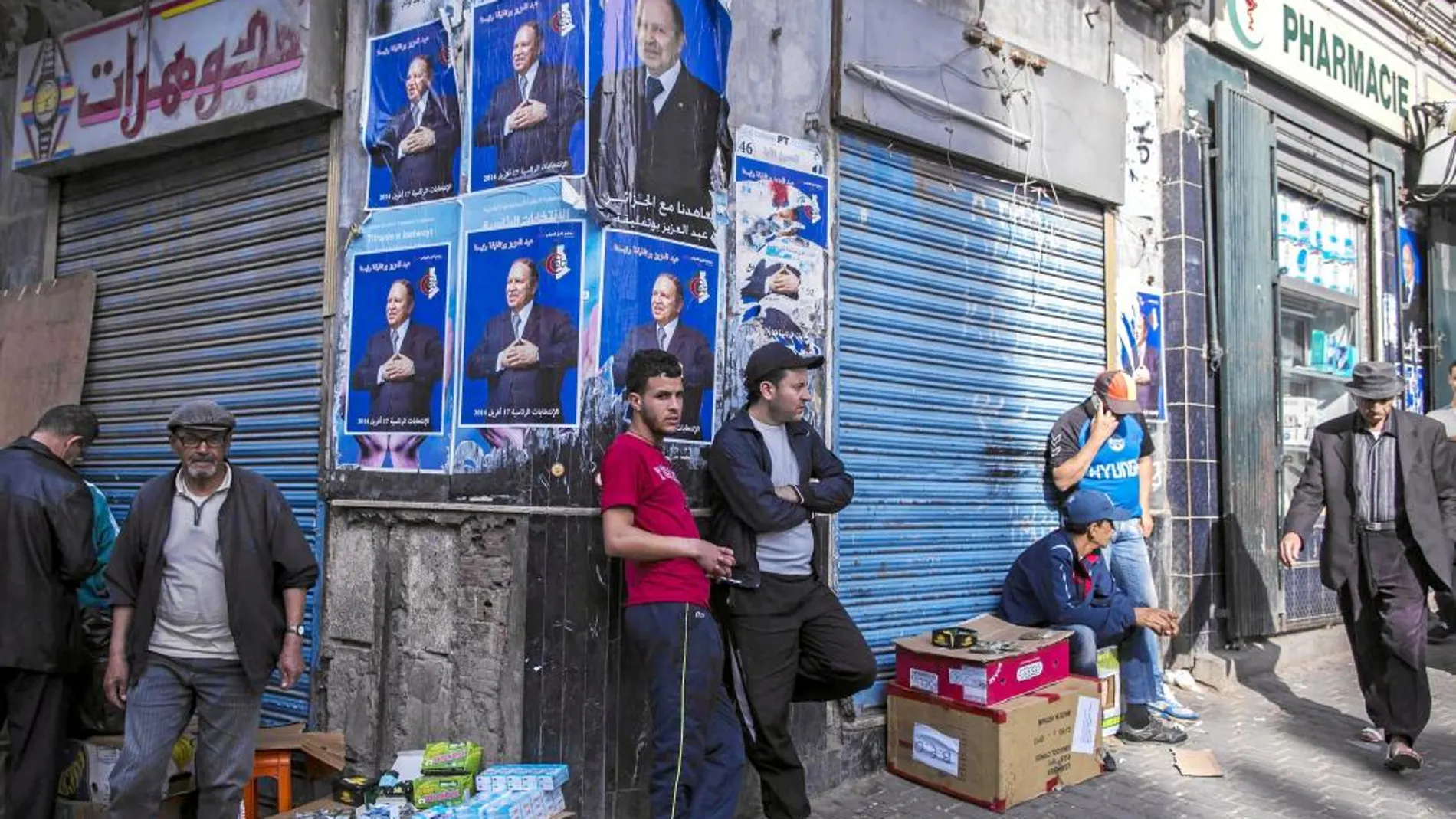 Varios argelinos, apostados sobre carteles electorales, ayer, en Argel