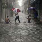 Filipinos cruzan una calle inundada por fuertes lluvias producidas por el paso del tifón Fung-Wong en Manila (Filipinas)