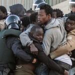 Los agentes de la Guardia Civil intentan contener a los subsaharianos tras el asalto a la valla de Melilla de hoy .