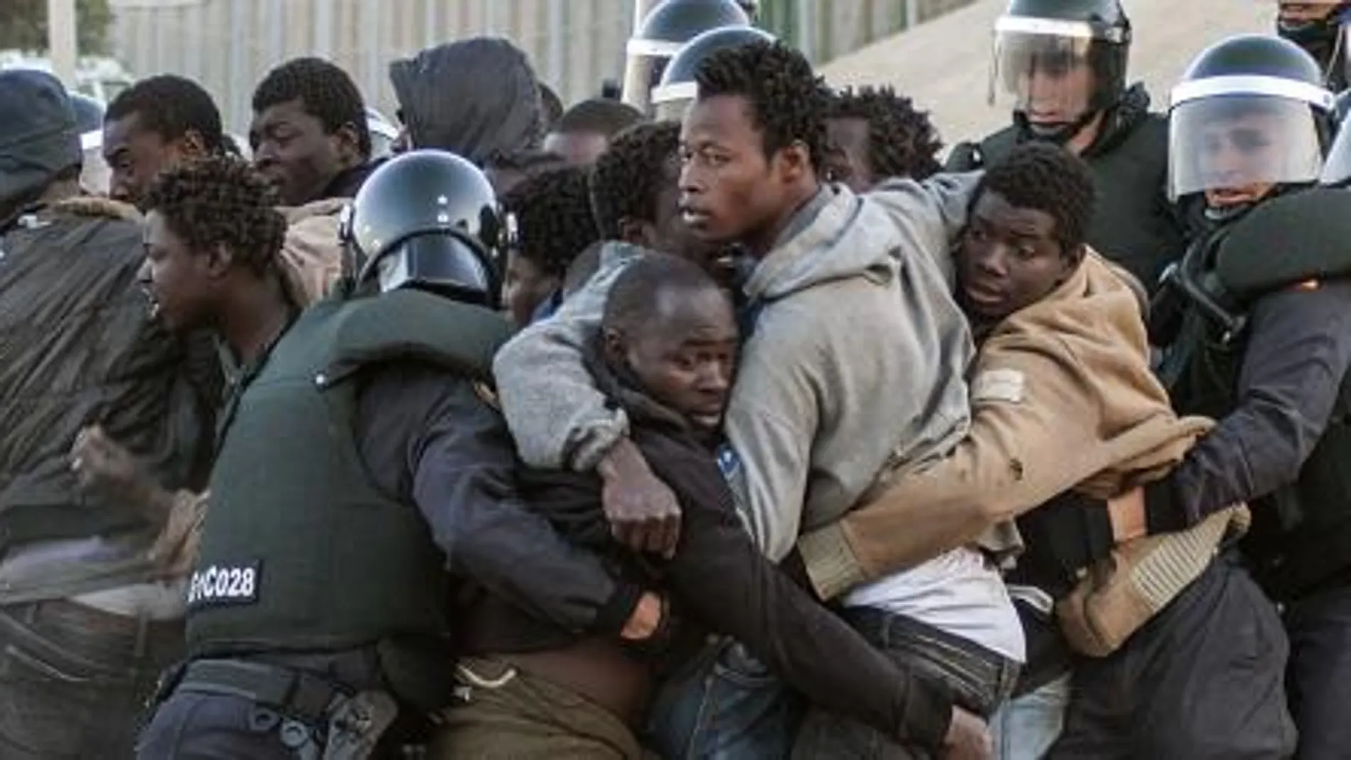 Los agentes de la Guardia Civil intentan contener a los subsaharianos tras el asalto a la valla de Melilla de hoy .