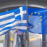 Un hombre colocaba ayer las banderas de Grecia y de la Unión Europea en la embajada helena de Bruselas
