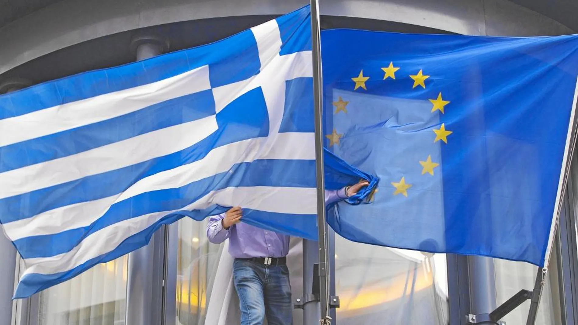 Un hombre colocaba ayer las banderas de Grecia y de la Unión Europea en la embajada helena de Bruselas