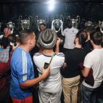 Varios turistas se hacen fotos ante las Copas de Europa del Real Madrid