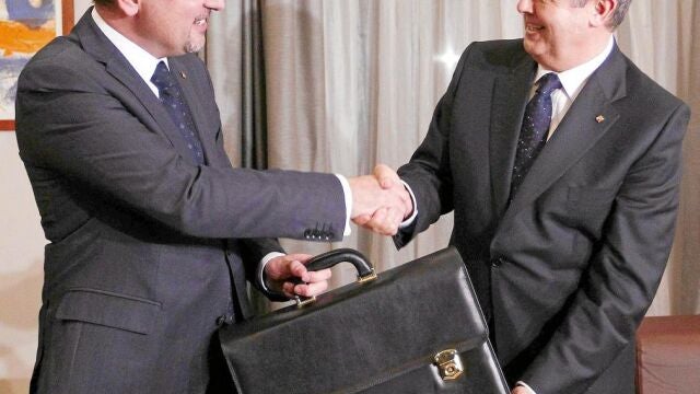 El nuevo conseller de Interior Ramon Espadaler (i) recibe de manos de su antecesor en el cargo, Felip Puig (d), la cartera como nuevo titular del Departamento, tras el acto de toma de posesión de los consellers celebrada esta tarde en el Palau de la Generalitat.