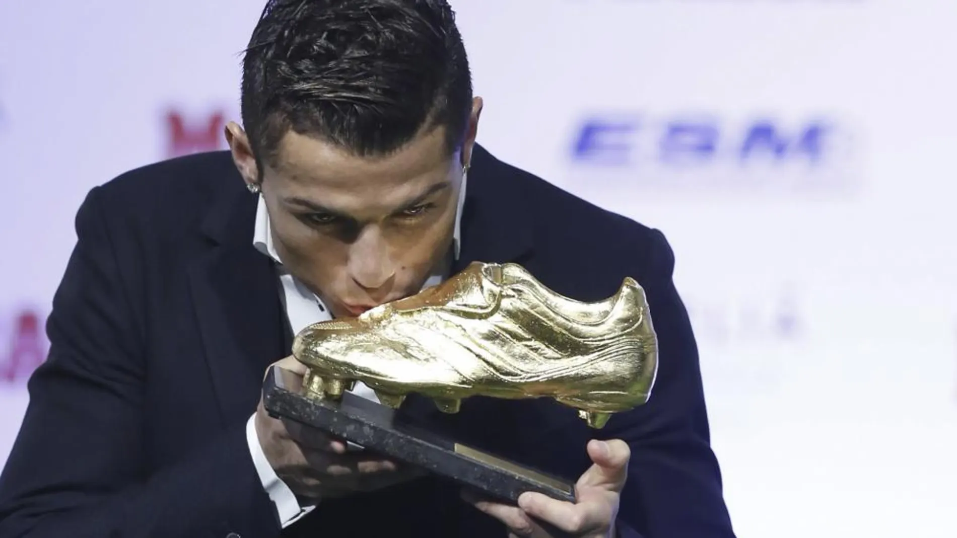 El delantero portugués del Real Madrid, Cristiano Ronaldo, besa la Bota de Oro 2013-2014, tras recibir el trofeo de manos de Florentino Pérez