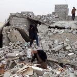 Varias personas buscan entre los escombros de su casa destruida por un grupo de chiíes armados al este de Tikrit en Irak