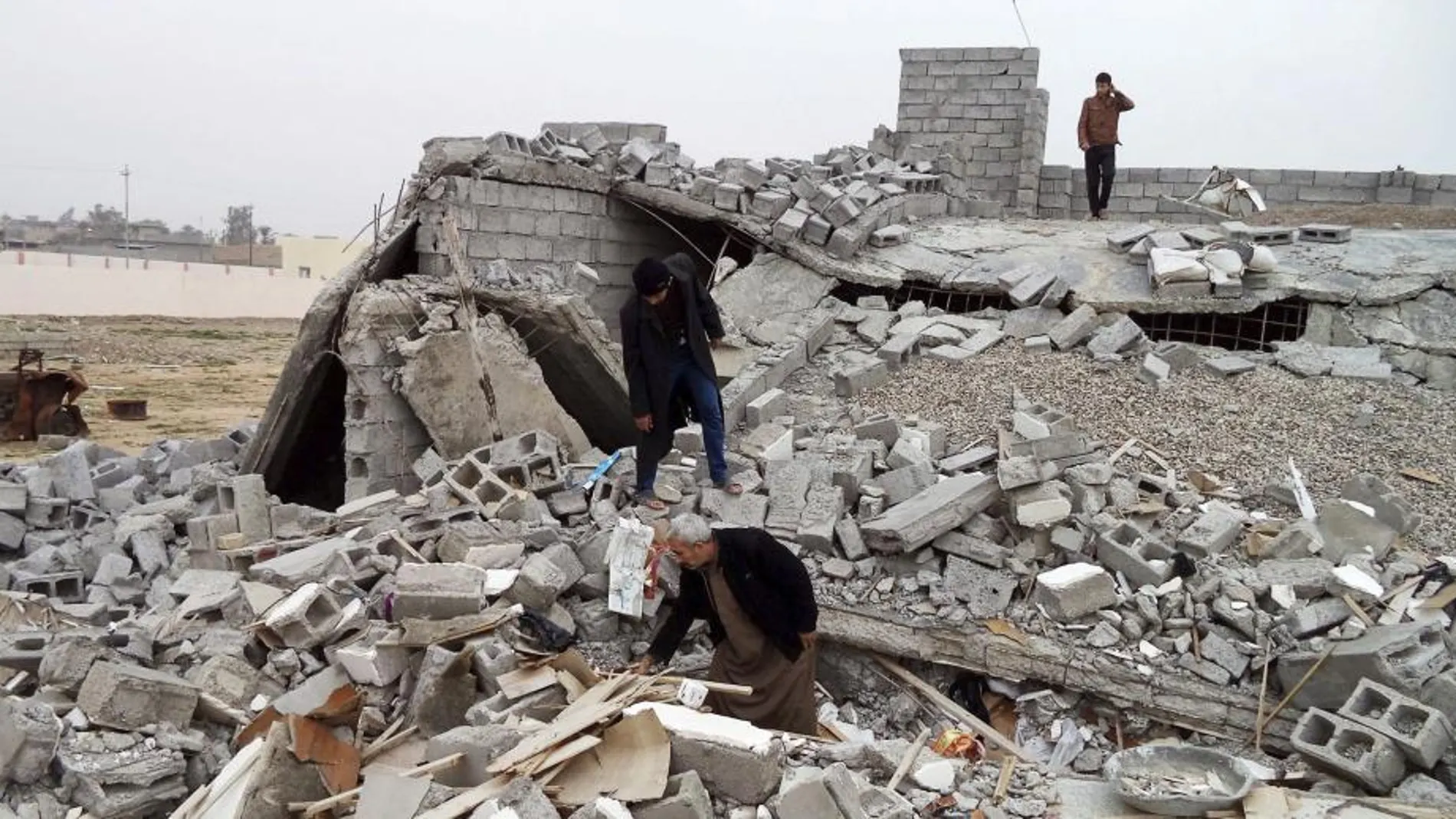 Varias personas buscan entre los escombros de su casa destruida por un grupo de chiíes armados al este de Tikrit en Irak