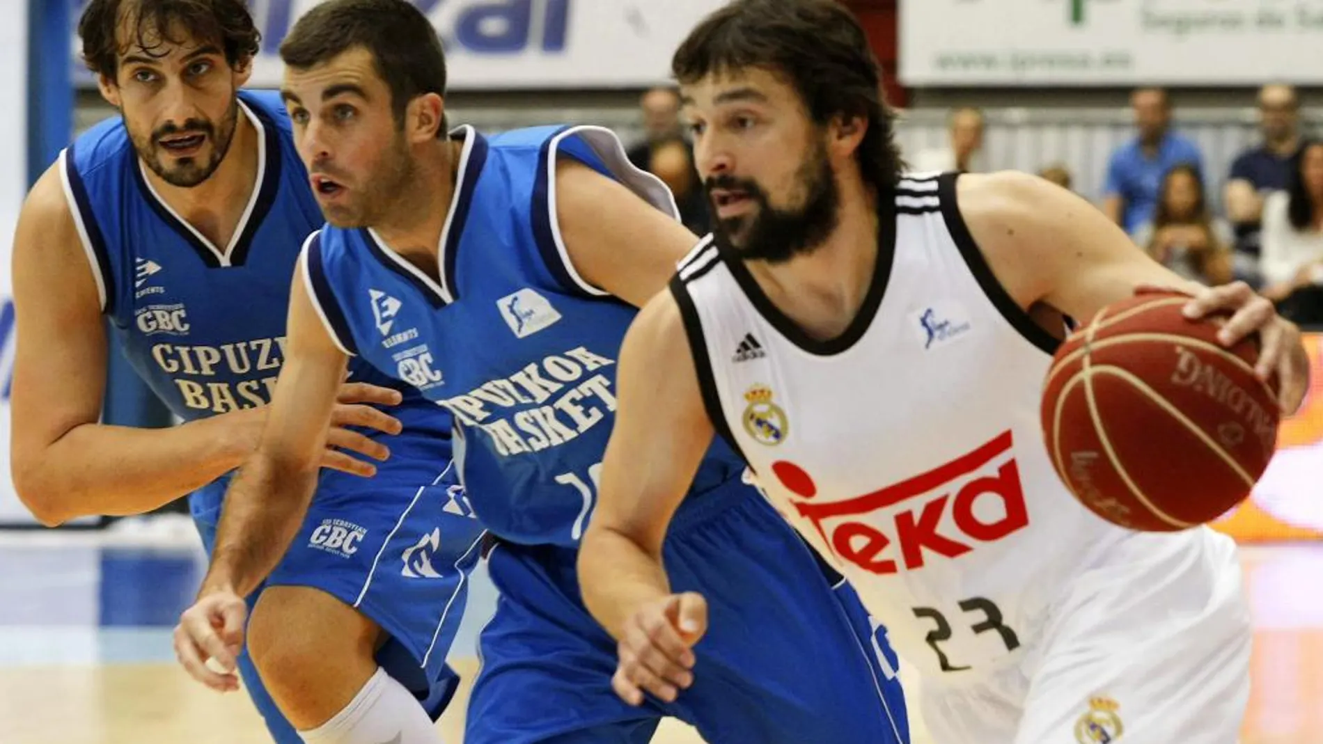 El base del Real Madrid Sergio Llull avanza con el balón ante los jugadores del Gipuzkoa Basket Jared Jordán y David Doblas, durante el partido de la segunda jornada de Liga ACB