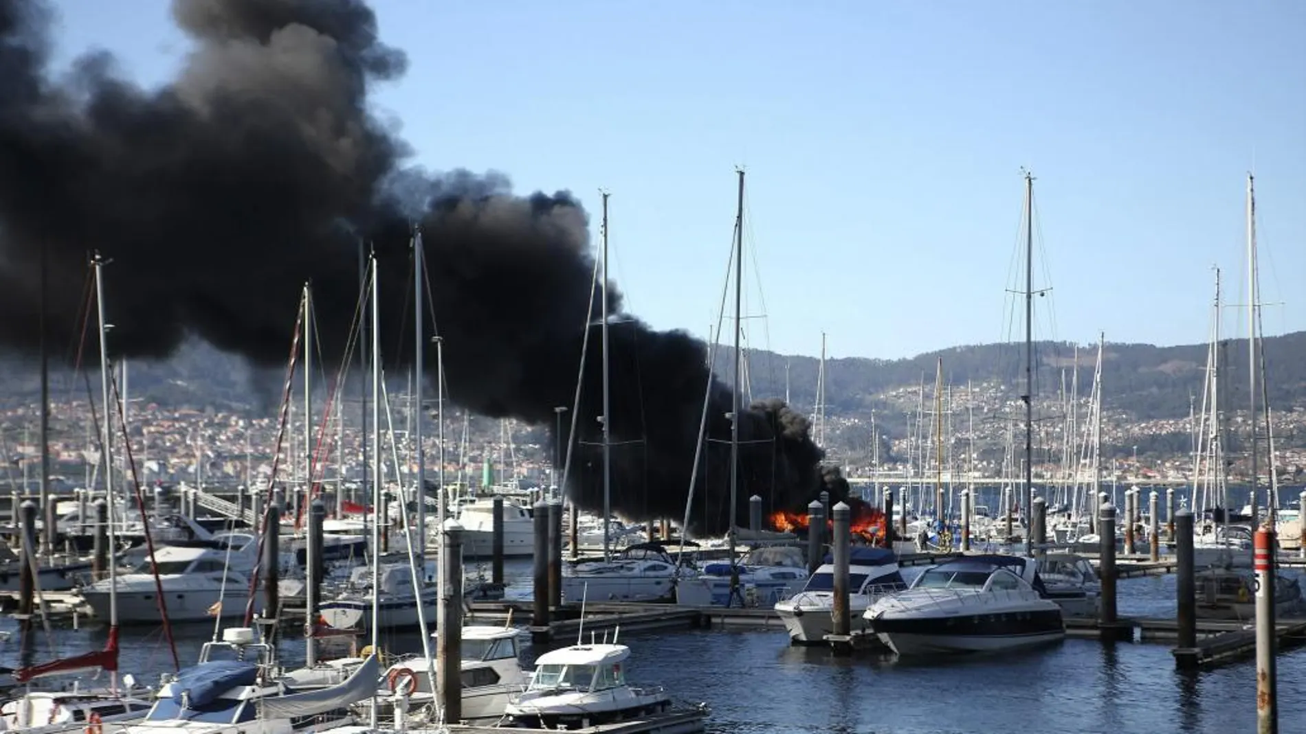 Vista del incendio del yate deportivo de unos 20 metros de eslora que se ha producido hoy en el puerto de Punta Lagoa, en Vigo
