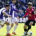El jugador del Almería Suso controla el balón ante los jugadores del Real Valladolid Jesús Rueda (i) y Víctor Pérez