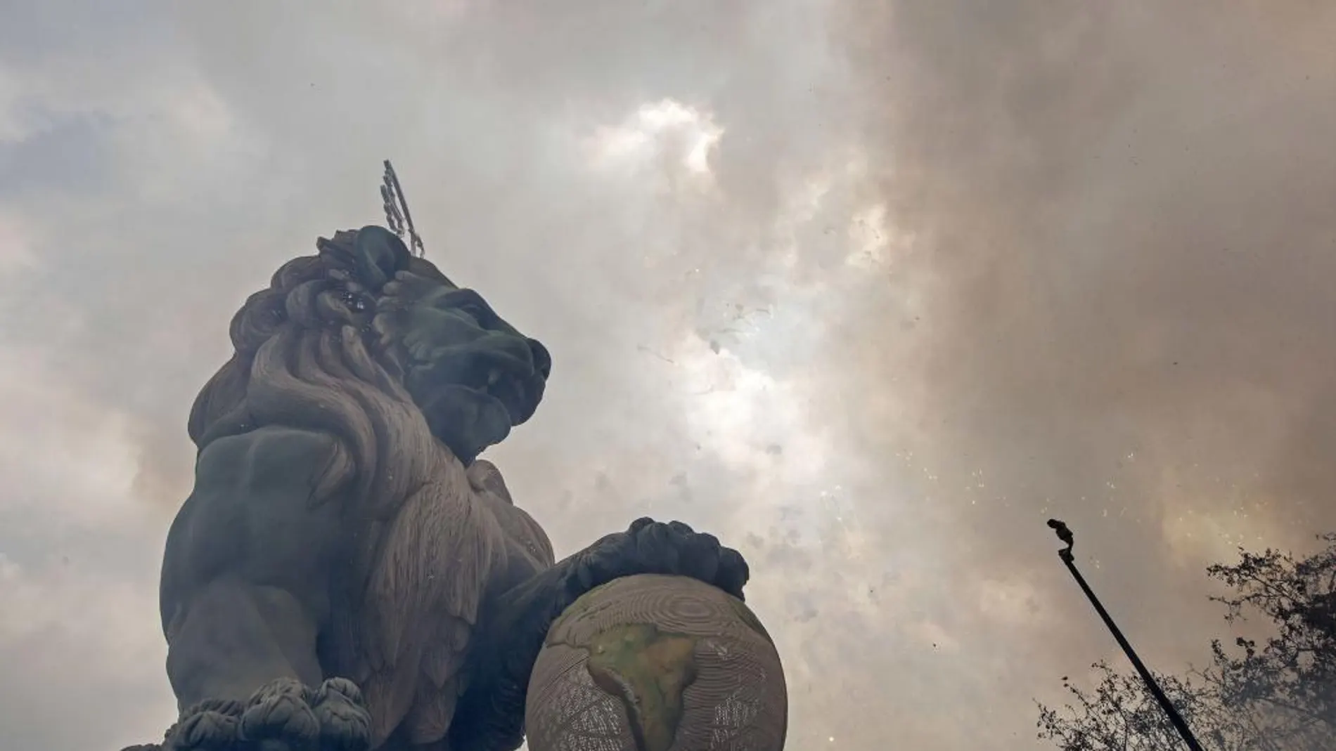 El León del Congreso de los Diputados que corona la falla de la Plaza del Ayuntamiento se ve envuelto en el humo de la polvora durante el disparo de la mascletá