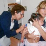 Una niña recibe una vacuna en un centro de salud de la Comunidad. Abajo, el nuevo calendario de vacunas de 2013
