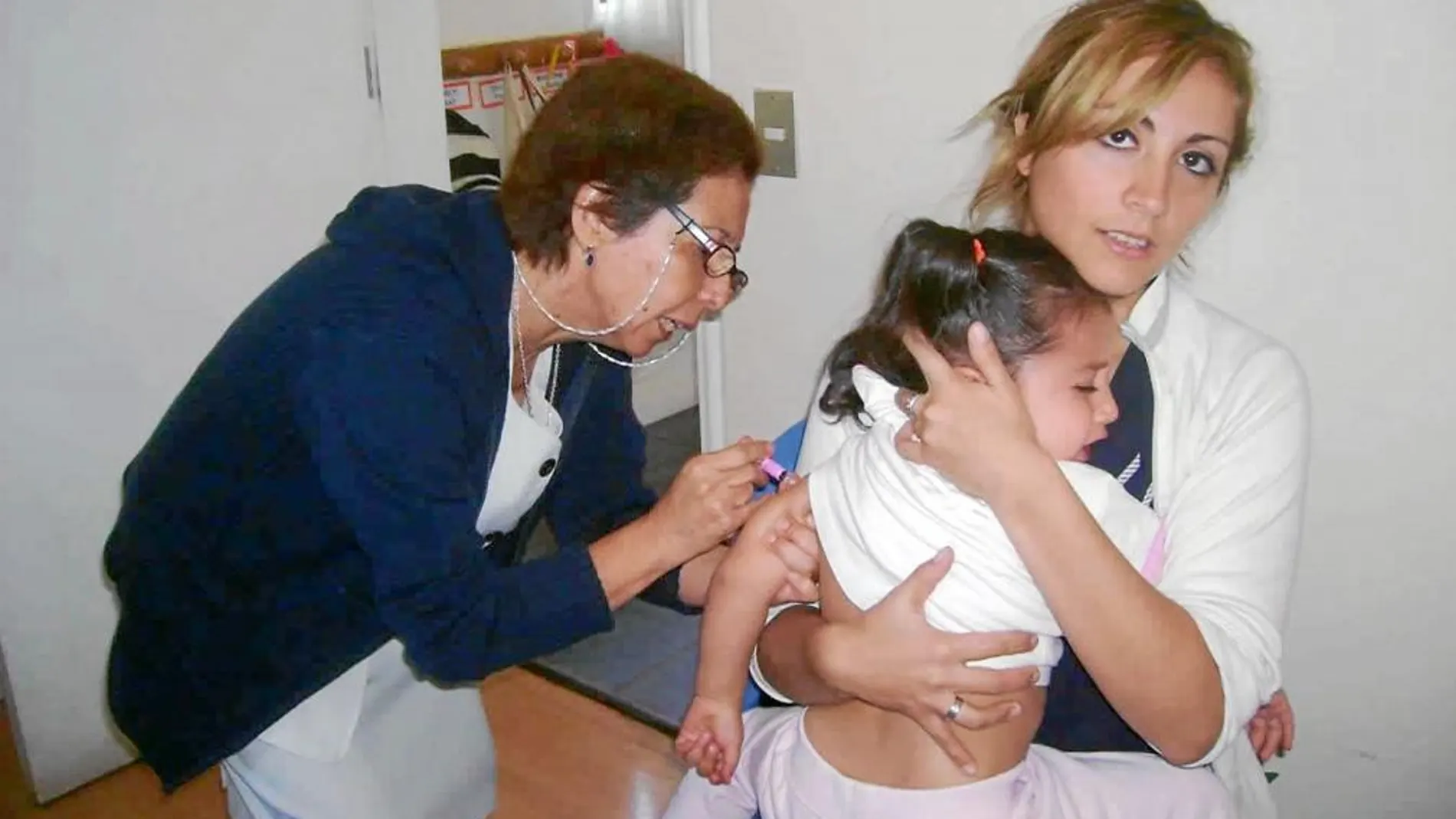 Una niña recibe una vacuna en un centro de salud de la Comunidad. Abajo, el nuevo calendario de vacunas de 2013