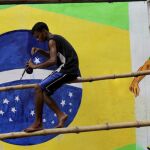 Un artista callejero pinta un mural con la bandera de Brasil y el delantero brasileño Neymar
