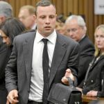 Oscar Pistorius se dirige a la salida de la sala del juicio después de la primera sesión. Al fondo se encuentra la madre de la modelo fallecida, June Steenkamp