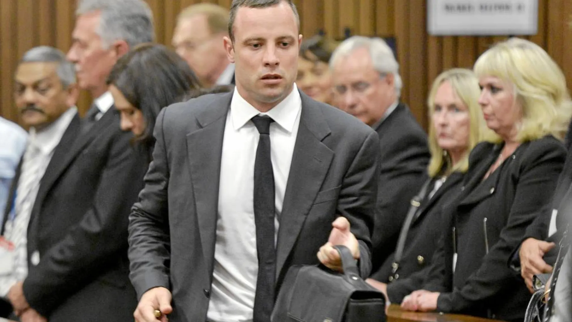 Oscar Pistorius se dirige a la salida de la sala del juicio después de la primera sesión. Al fondo se encuentra la madre de la modelo fallecida, June Steenkamp