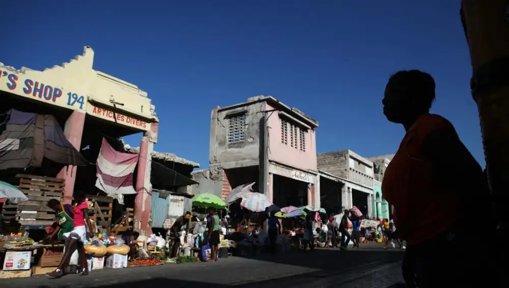 Varias personas caminan cerca de las ruinas de los locales comerciales de la avenida Desallines, destruidos durante el terremoto del 12 de enero de 2010, en Puerto Príncipe (Haití)