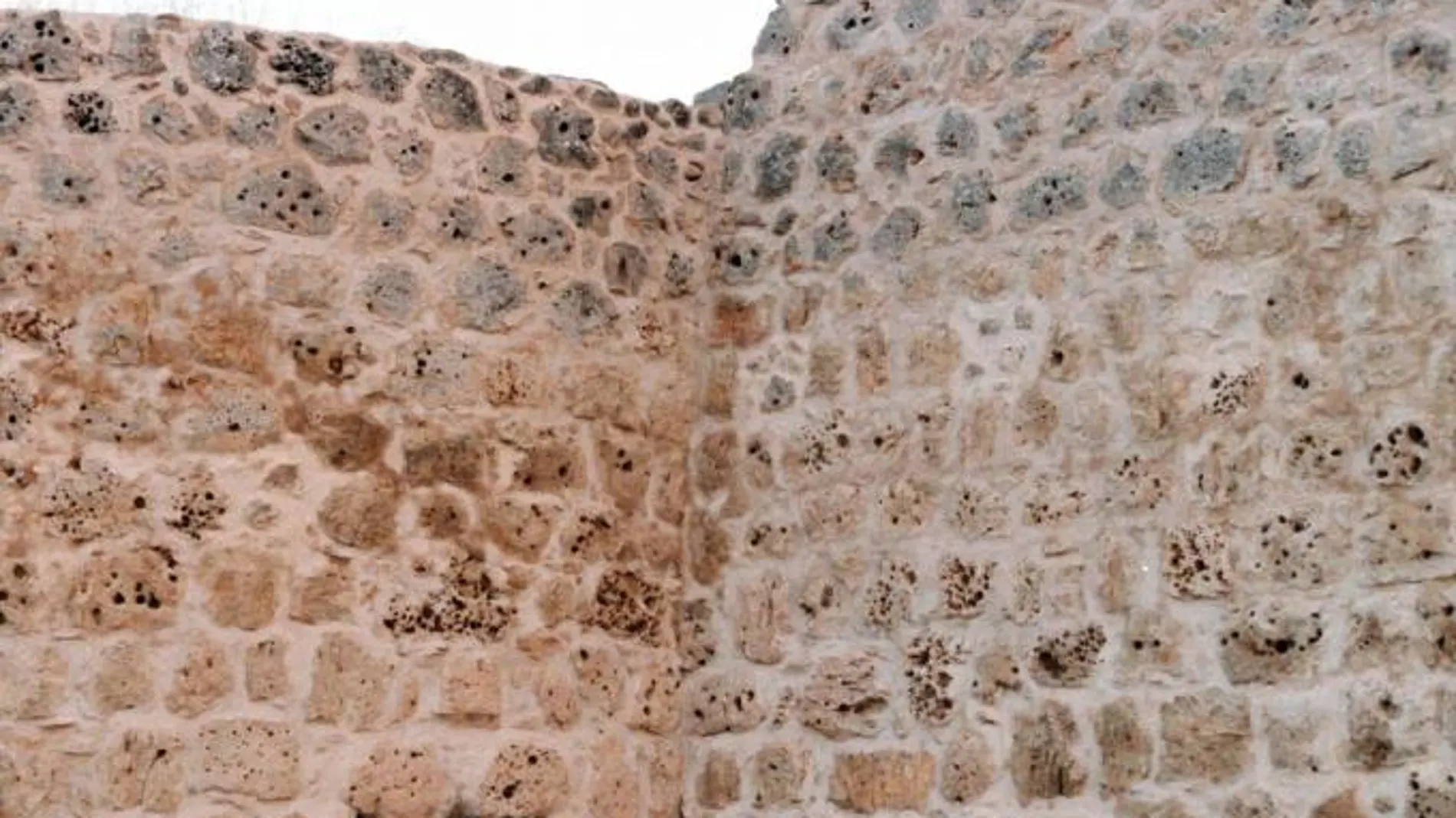 Un hombre entra en un cubo en la muralla de Urueña, que estaba oculto por un antiguo pajar adosado