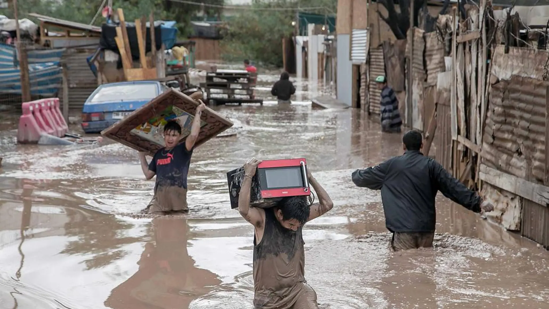 Varios vecinos tratan de poner a salvo algunas de sus pertenencias tras desbordarse un río, en Copiapó (Chile)