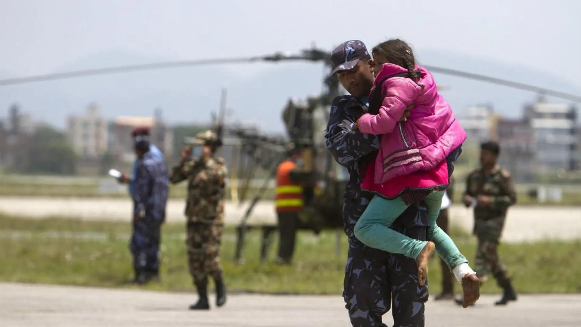 Un soldado nepalí traslada a una niña herida tras ser rescatada en Sindhupalchock, a su llegada al aeropuerto Internacional de Katmandú.