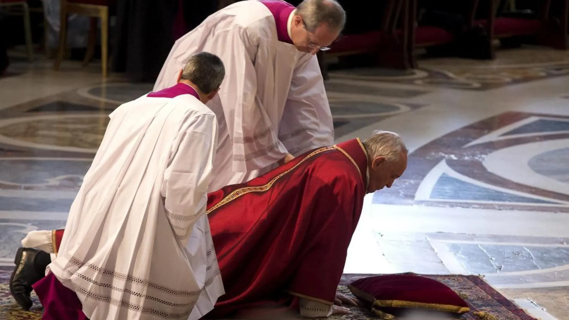 Francisco es ayudado al levantarse del suelo durante la misa de Viernes Santo oficiada en la Basílica de San Pedro en el Vaticano.