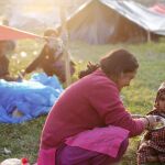 AUna mujer da de comer a su hija en un campamento para los desplazados