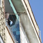 Un policía examina el balcón de una vivienda Granada desde donde cayo un bebé de aproximadamente un año que ha resultado muerto.